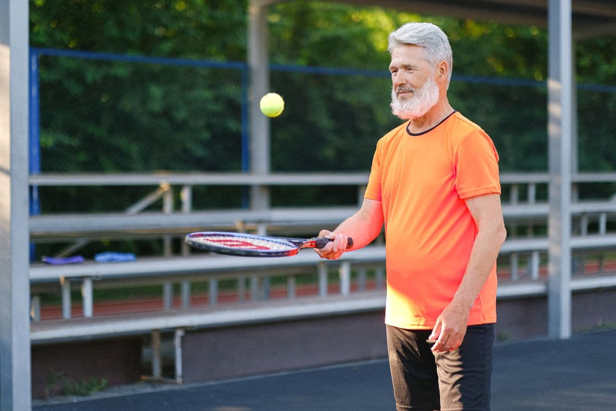 A cheerful older player walking onto the court
