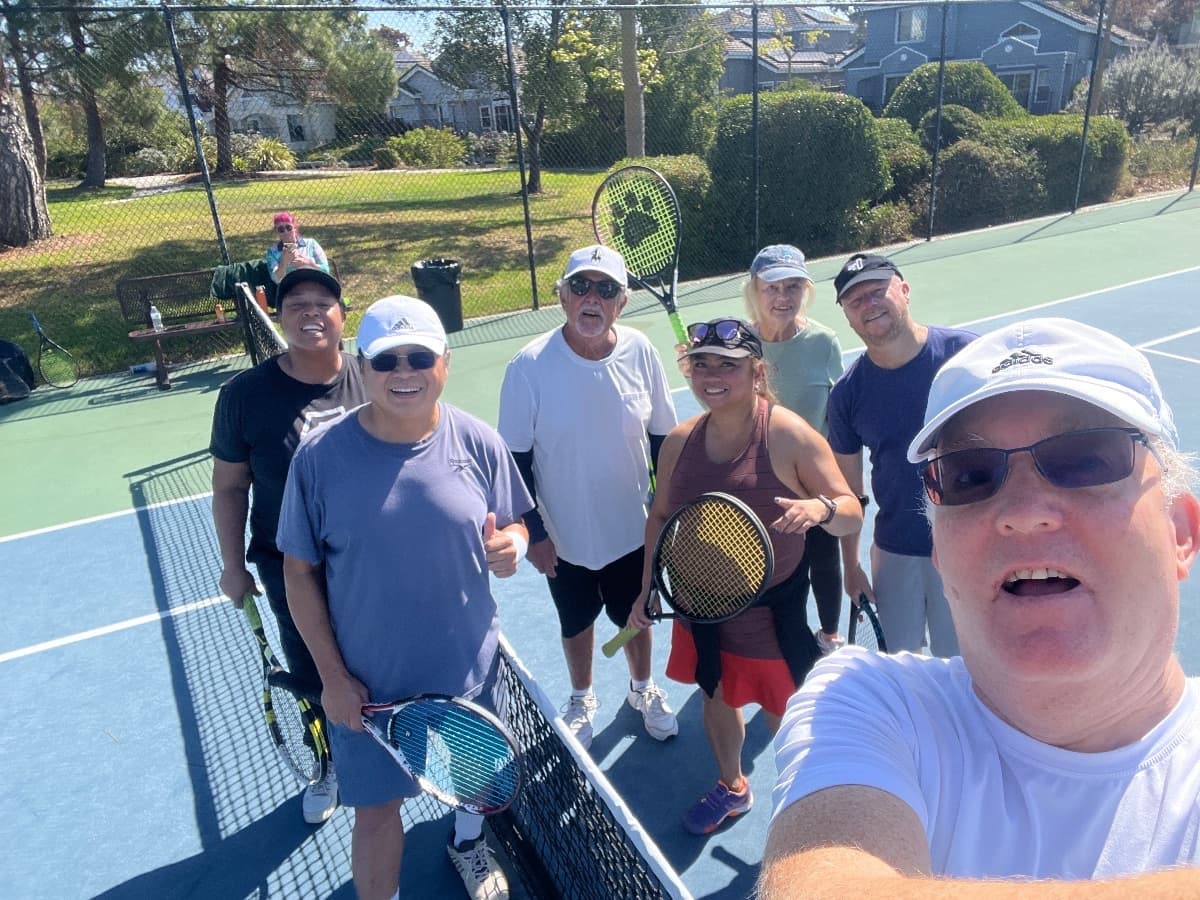 A big group of players smiling in a selfie at the net